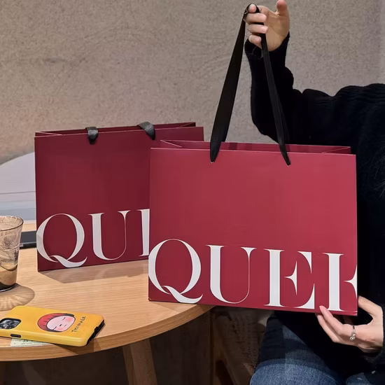 Cadeaux personnalisés de luxe Sacs en papier imprimés avec logo Kraft Vêtements Sacs à provisions avec poignées Rivets Sac fourre-tout en papier pour transporter des vêtements cosmétiques